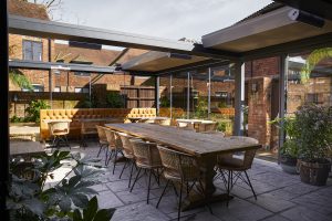 Outdoor table and chairs protected by retractable roof
